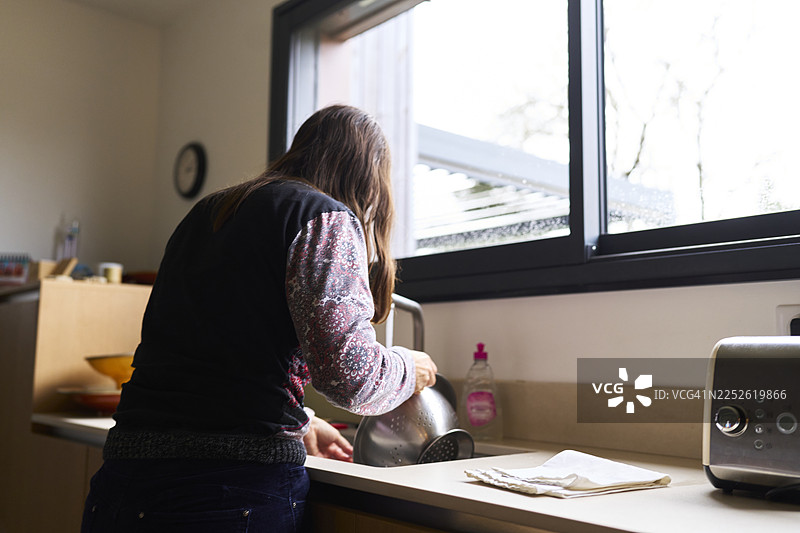 女人在厨房水槽旁窗户边洗碗图片素材