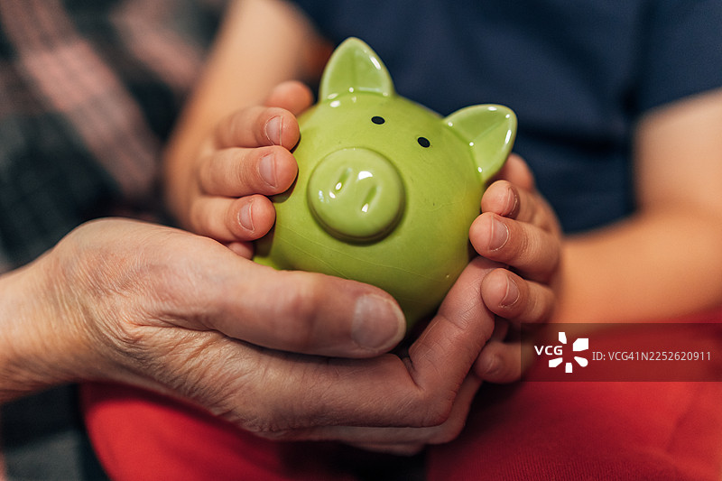 孩子和祖父母的手握着储蓄罐，教导储蓄图片素材