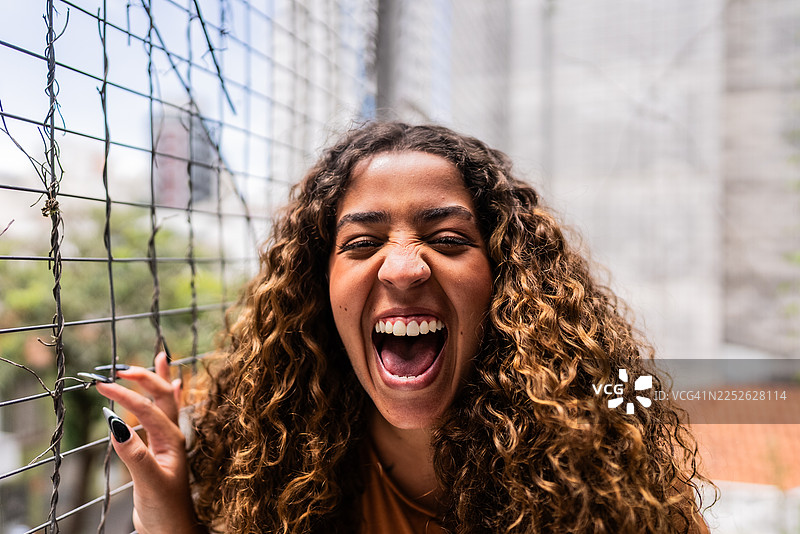 公寓屋顶上，兴奋的年轻女子大笑的肖像图片素材