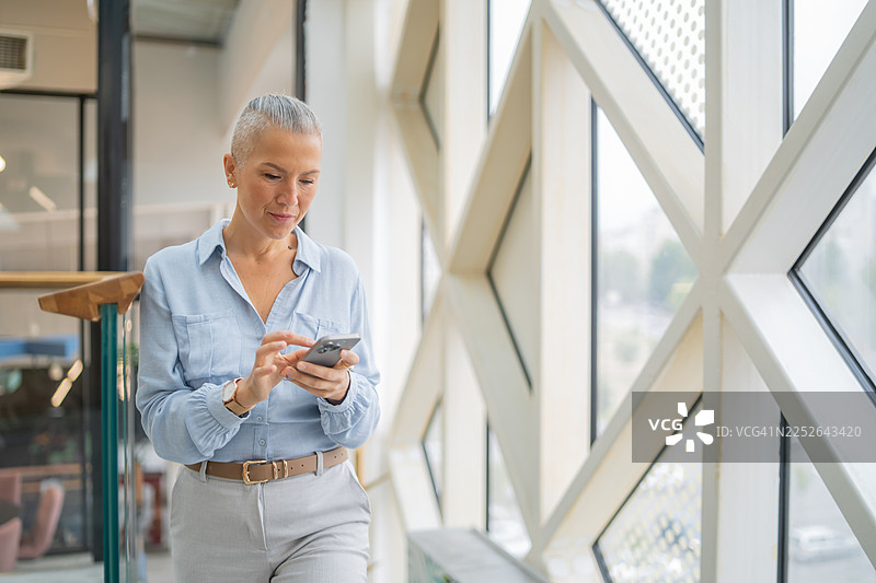 女商人使用智能手机在现代办公楼里图片素材