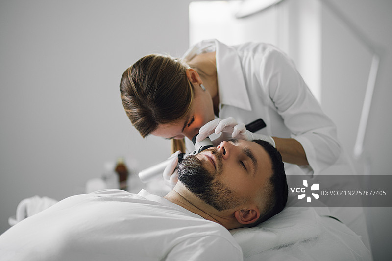 女皮肤科医生使用现代医疗设备分析患者皮肤图片素材