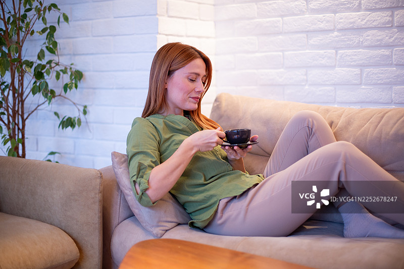 女人在家放松，享受一杯热咖啡图片素材