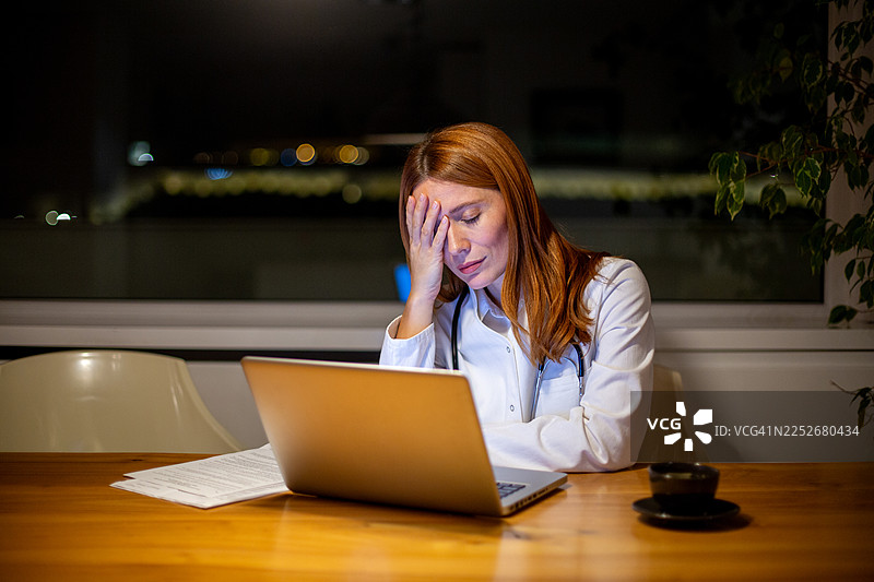 一名疲惫不堪的医生在深夜加班，感到身心俱疲、不堪重负图片素材