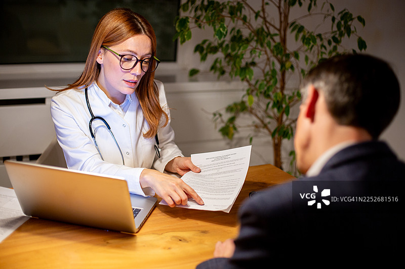 医生在办公室与男病人讨论医疗文件图片素材
