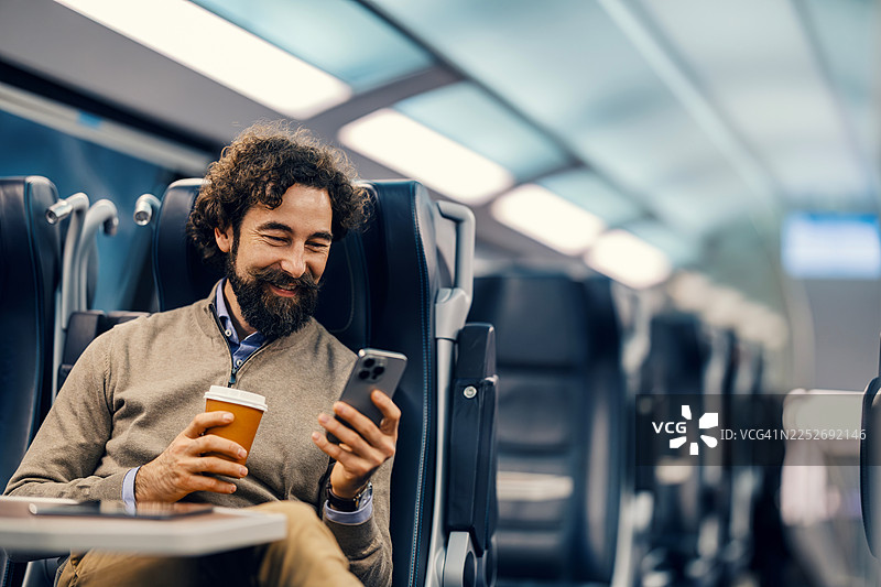 男人在火车上喝咖啡并使用智能手机图片素材