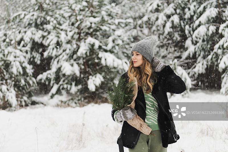 年轻女子置身于白雪覆盖的森林中，周围是雪树和原始的冬季景观。图片素材