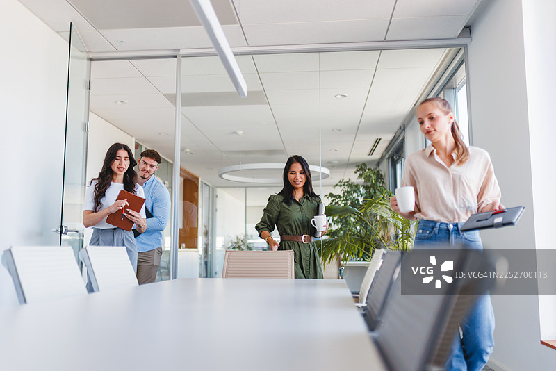 年轻的商务高管带着笔记本电脑和咖啡进入董事会议室图片素材