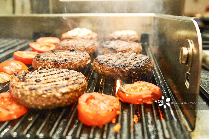 餐厅烤架上正在烤制的汉堡和番茄图片素材
