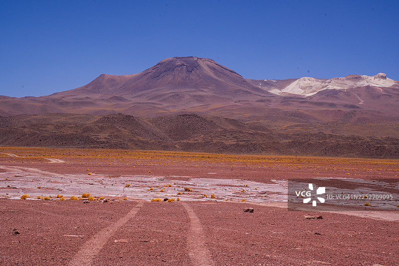智利沙漠的干旱地貌和沙丘，远方是塞罗米斯坎蒂火山，天空湛蓝晴朗图片素材