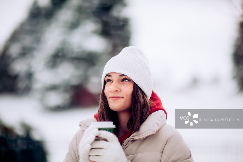 一位18岁的年轻女子在冬日户外饮用热咖啡图片素材