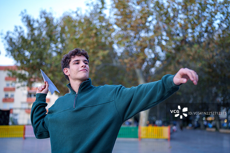 年轻男子在户外放飞纸飞机，象征着自由图片素材