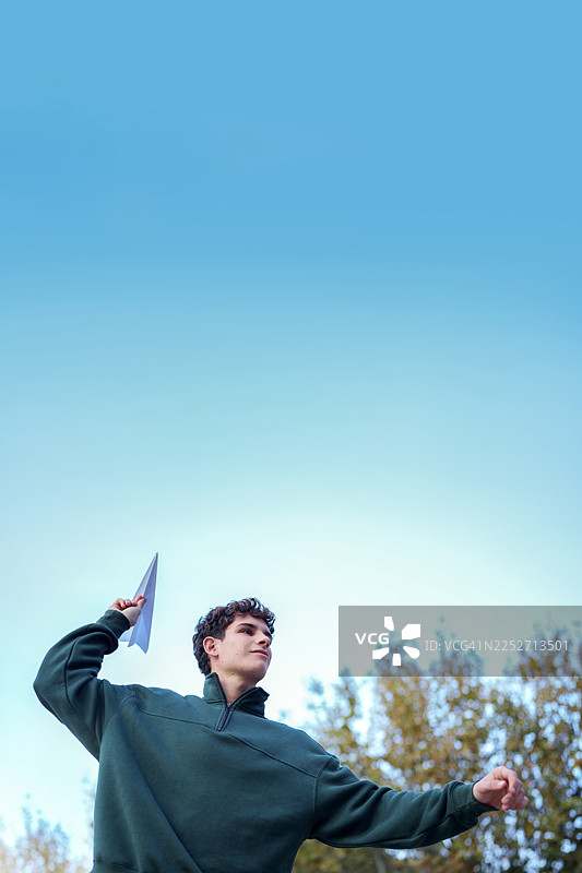 年轻男子在蓝天下放飞纸飞机图片素材