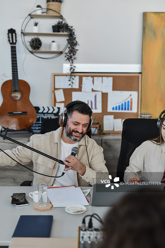 创意办公室里的休闲播客录音棚场景，有主持人、联合主持人、麦克风和笔记本电脑图片素材