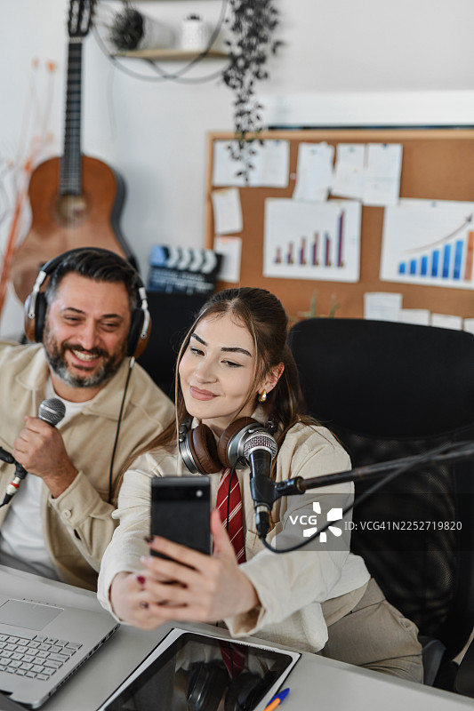 主持人与嘉宾在录音棚里自拍的友好播客瞬间图片素材