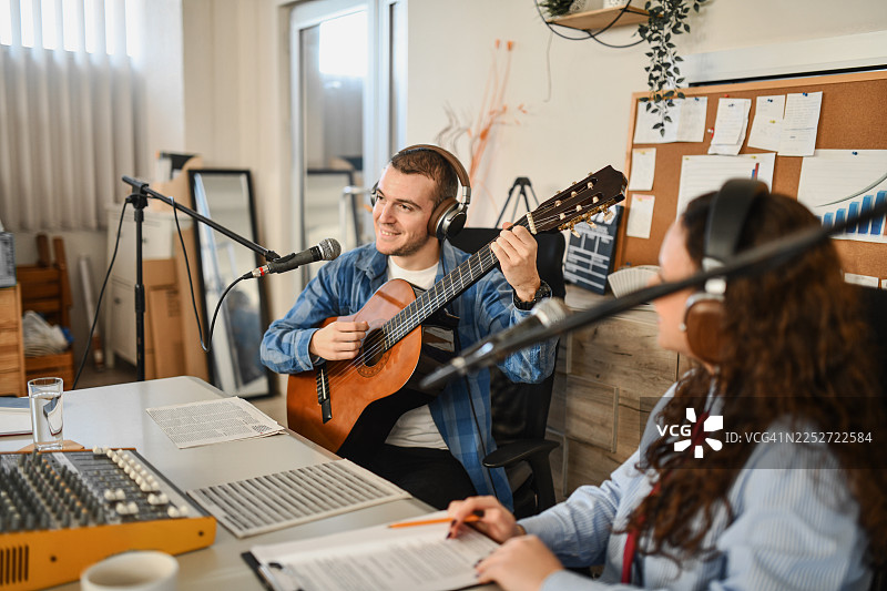 音乐嘉宾在舒适的录音室里弹奏木吉他，同时被录制成播客图片素材