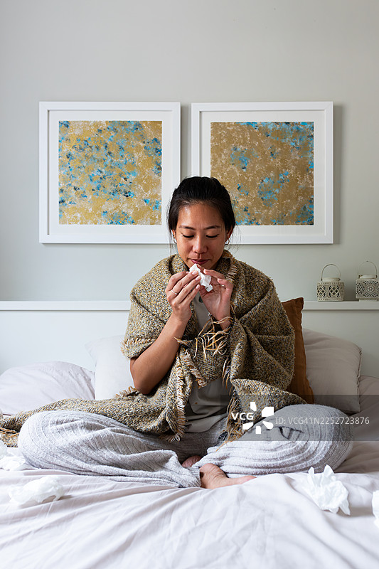一名年轻女子躺在床上，感到流感不适图片素材