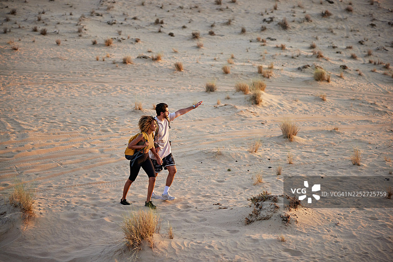 一对情侣在沙漠沙丘中徒步探险图片素材