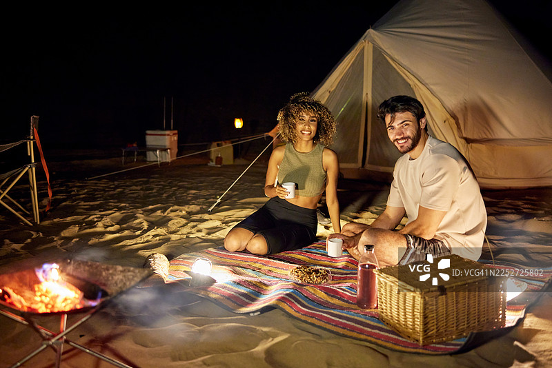 年轻夫妇在迪拜沙漠享受浪漫的夜间露营图片素材