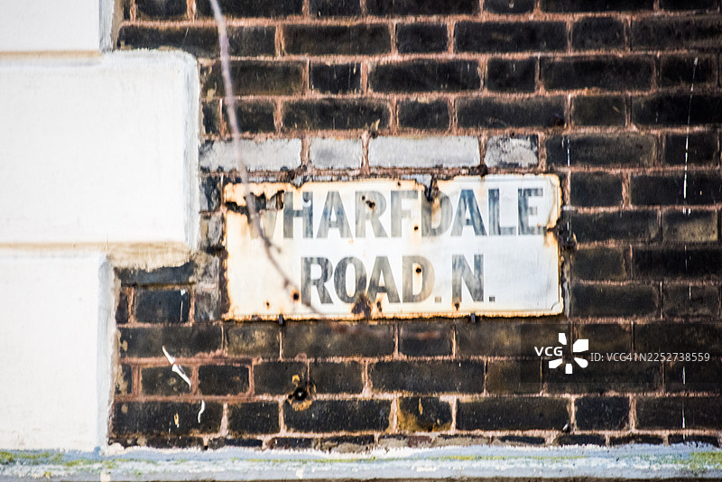 锈迹斑斑的沃夫戴尔路牌，背景是深色砖墙图片素材