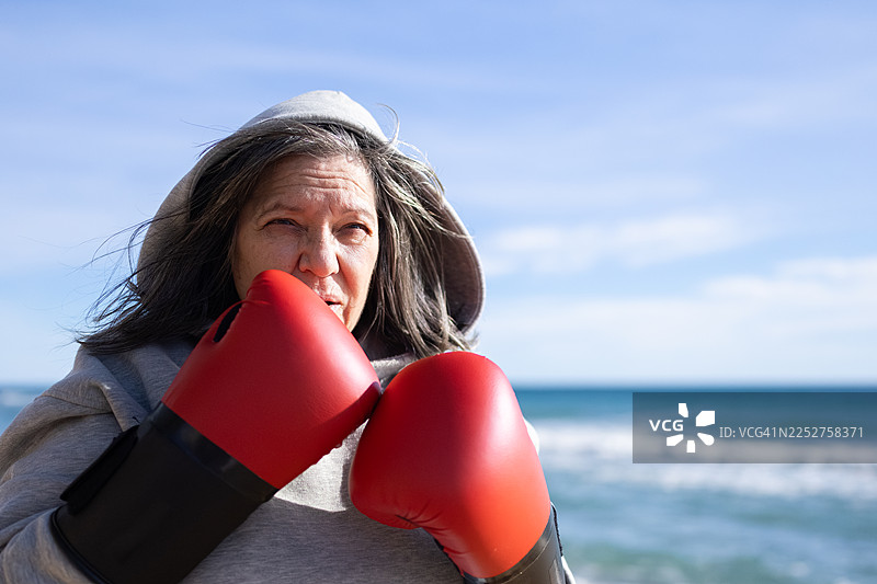 海滩上戴着拳击手套打拳的年长女性图片素材