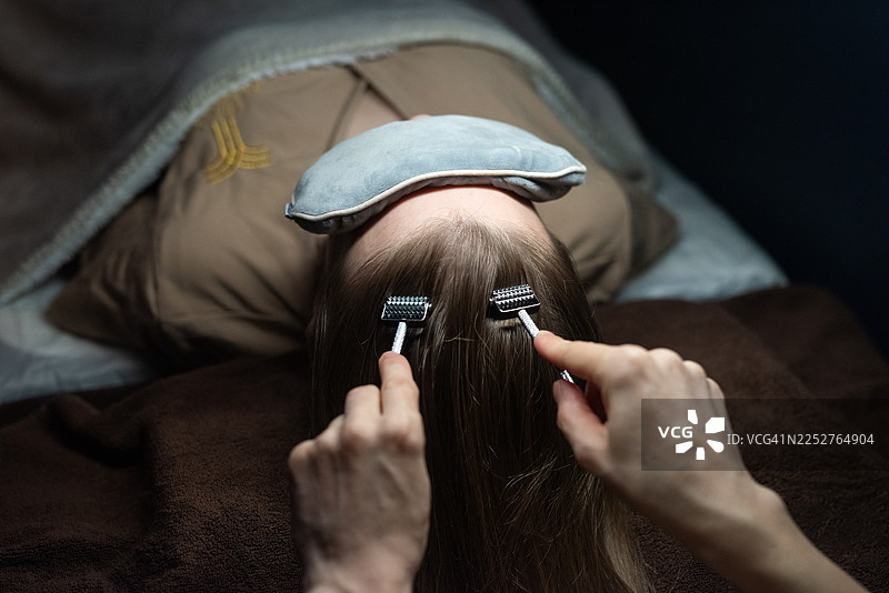 一位不知名的女性正在使用滚针进行头皮护理。图片素材