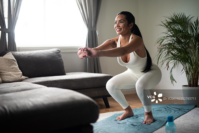 运动健将正在家做瑜伽垫上的深蹲锻炼。图片素材