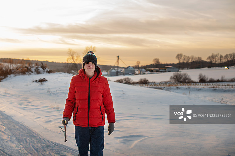 患有自闭症的男性在雪中的圣诞树农场拿着锯子。在新泽西州波科诺斯乡村环境中，冬日落时分的家庭节日活动。图片素材