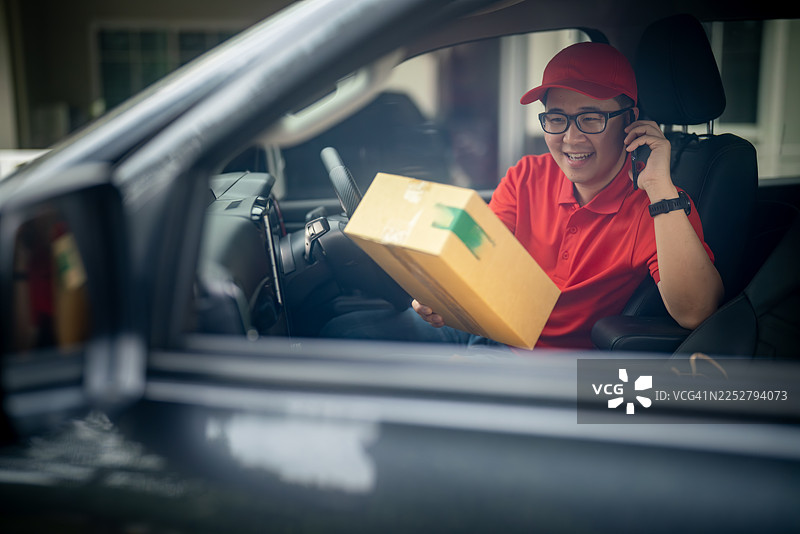 送货员一边拿着顾客的包裹一边打电话图片素材