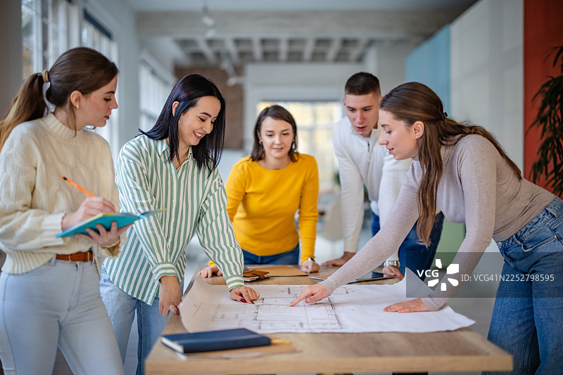 一群成年人在现代办公室环境中进行工作会议，规划和讨论项目细节图片素材