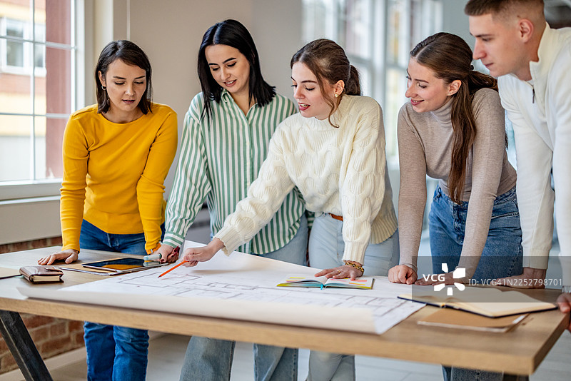 一群成年人在现代办公室环境中，在工作时间内讨论计划并协作开展项目。图片素材