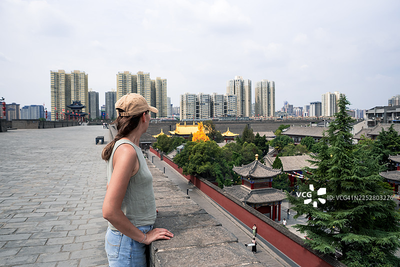 一位年轻女子在城墙上欣赏西安市景，但无法辨认出她的身份图片素材