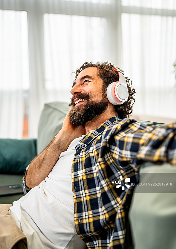 留着胡子的男人正躺在沙发上听音乐图片素材