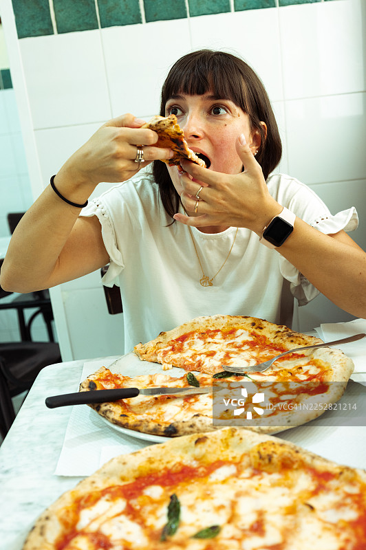 一位女士在餐厅里吃披萨。图片素材