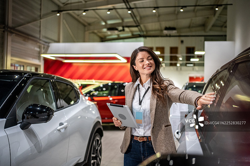 汽车销售人员手持平板电脑展示新车图片素材