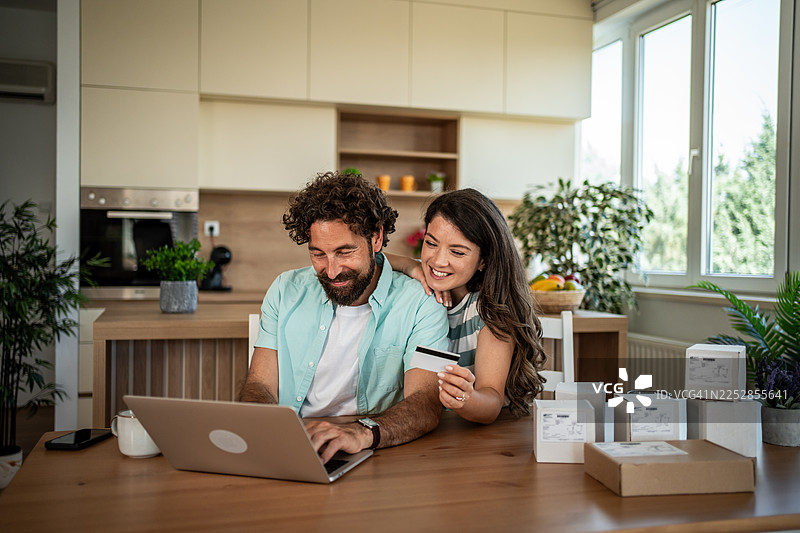 一对快乐的夫妇正在使用笔记本电脑和信用卡进行在线购物图片素材
