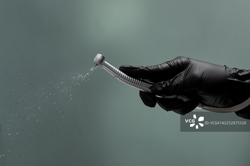 牙医手持带喷水功能的牙钻进行口腔护理，专业牙科护理，医药与牙科图片素材