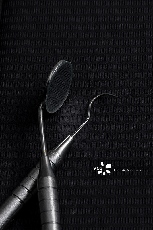 深色牙科托盘上的牙科镜和探针，准备进行口腔卫生和牙科检查图片素材