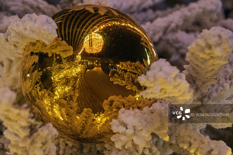 雪松树上装饰着一个大圣诞装饰球，上面映着美丽的雪景图片素材