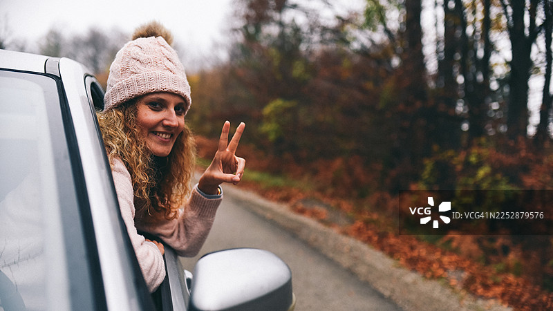 秋日公路，女子探身车窗外，享受惬意户外探险图片素材