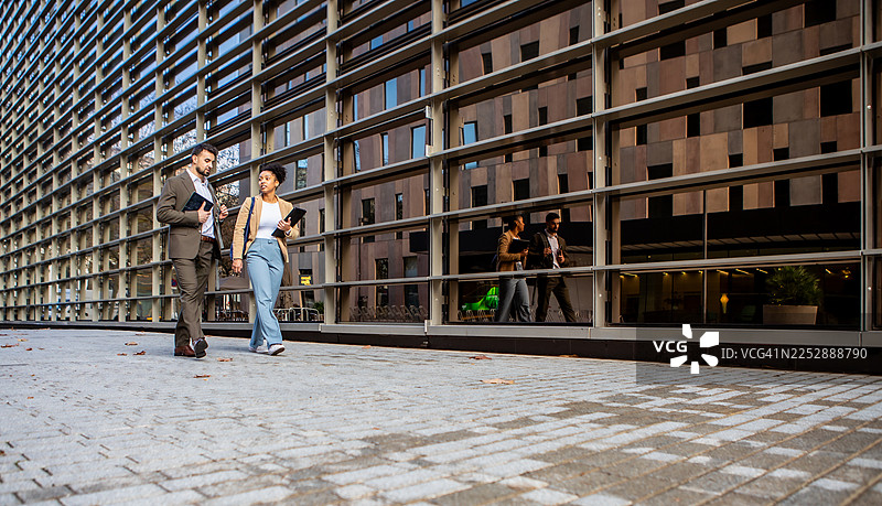 商务人士在城市街区边走边谈图片素材