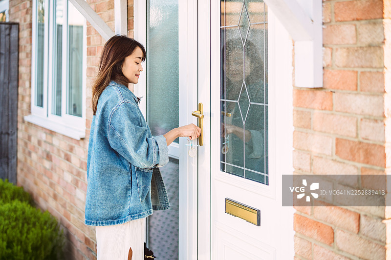 女子用钥匙打开现代住宅的前门图片素材