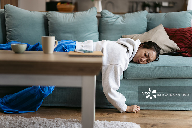 女性在家中因职业倦怠而筋疲力尽地躺在沙发上图片素材