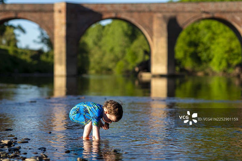 蹒跚学步的孩子在河里玩耍图片素材