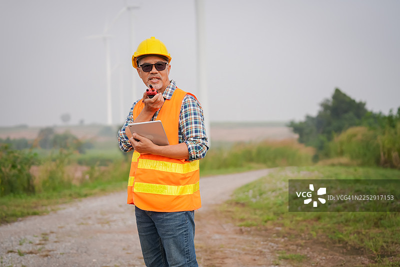 建筑工人使用平板电脑监控农村地区的风电场运营，数字洞察，户外环境，近景视角图片素材