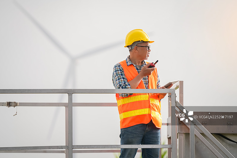 建筑工人在风电场工业区进行户外侧视监控作业，项目管理图片素材
