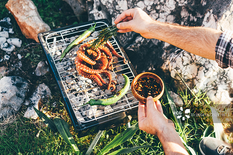新鲜的章鱼和青椒在户外便携式炭火烤架上烹饪图片素材