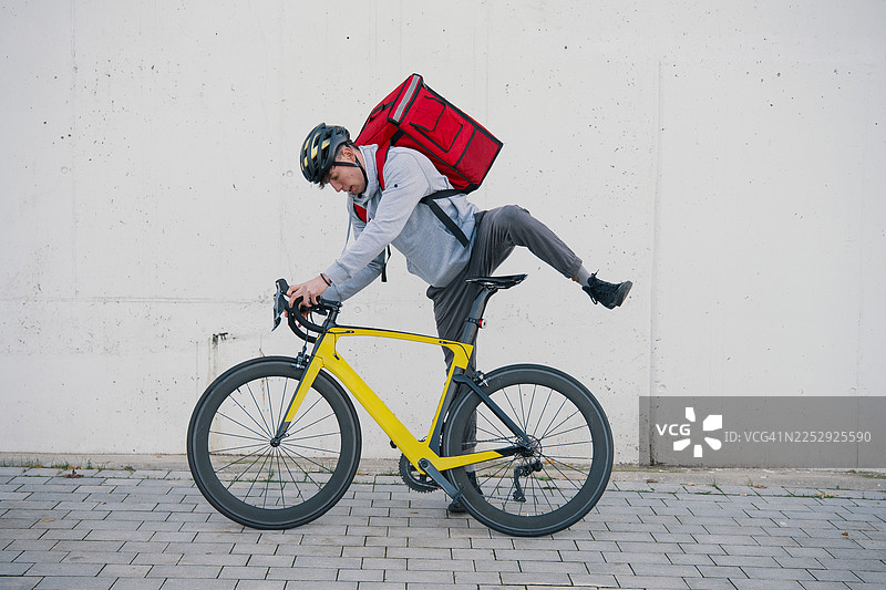 骑行者正骑上一辆载有外卖背包的黄色自行车。图片素材