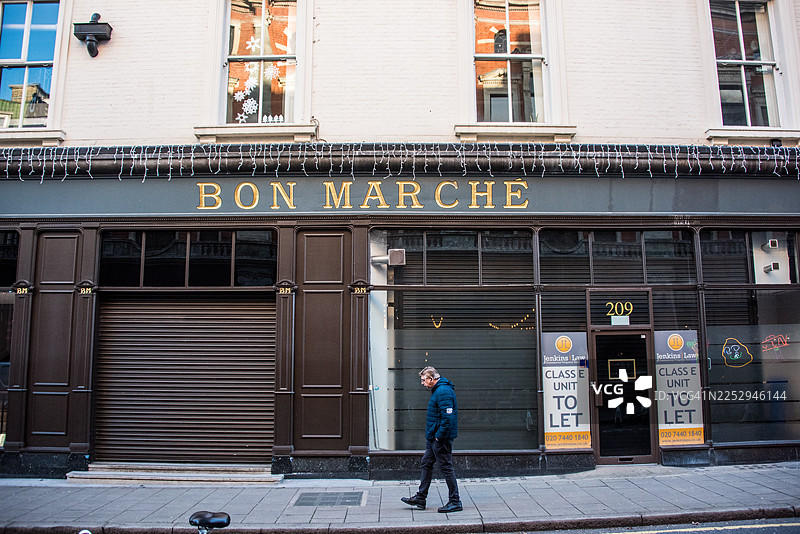 男子走过伦敦布里克斯顿已关闭的邦马歇百货大楼图片素材