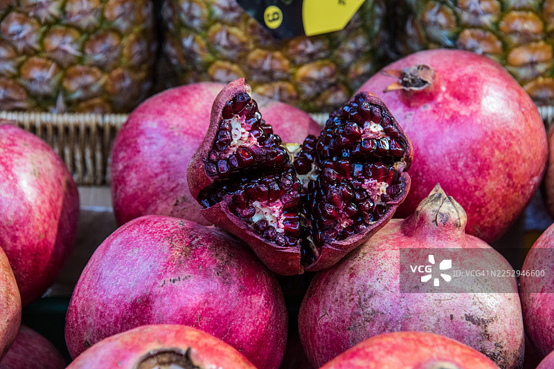 市场上展示着裂开的石榴，露出红色的籽图片素材
