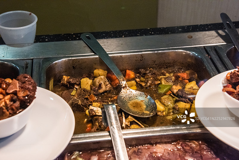 熟食摊上的不锈钢托盘装着牛尾炖菜图片素材
